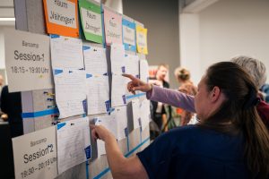 Einblicke in das Netzwerktreffen der Allianz für Beteiligung in Tamm: Auf diesem Bild sieht man Teilnehmende, die am Session-Board über einzelne Angebote miteinander diskutieren.